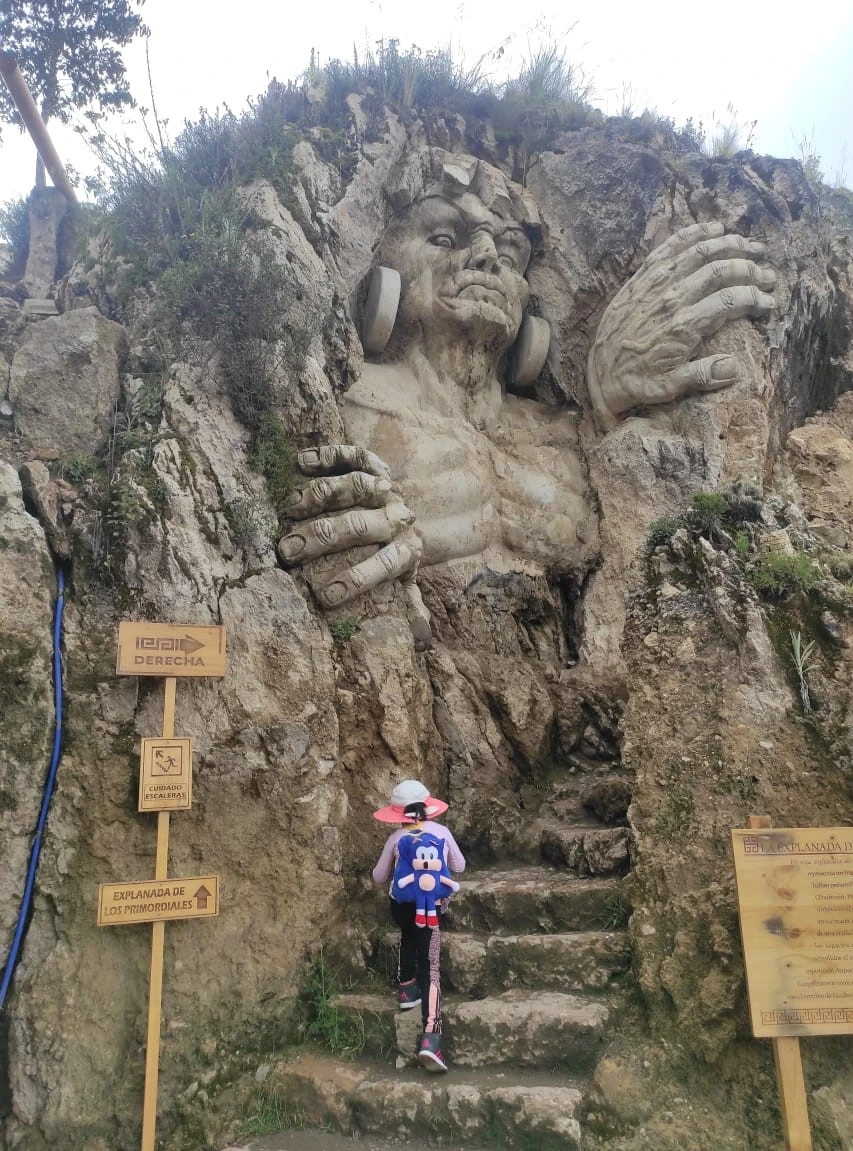 Visitor standing by giant stone face at the Abode of the Gods in Cusco.