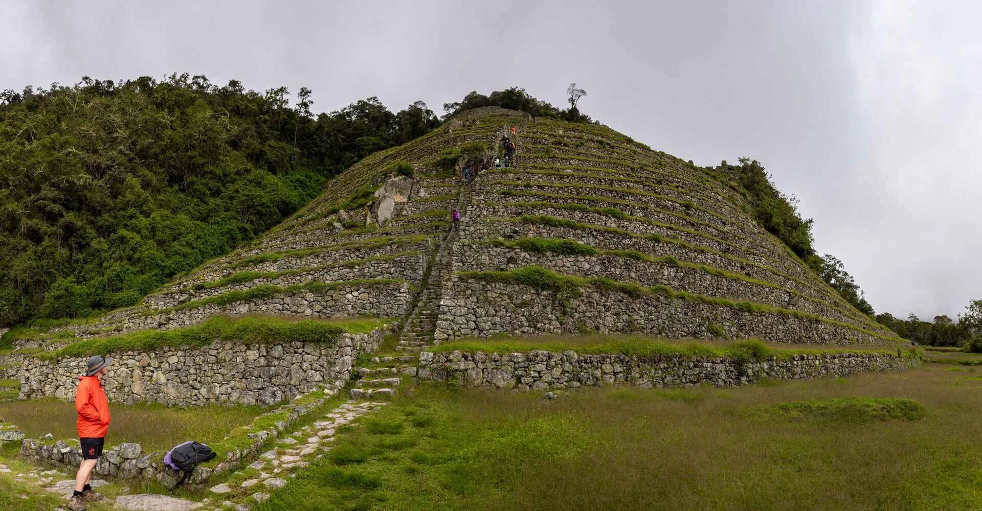 Hikers walking the Inca Trail to Machu Picchu, passing through Inca terraces and Andean mountains.