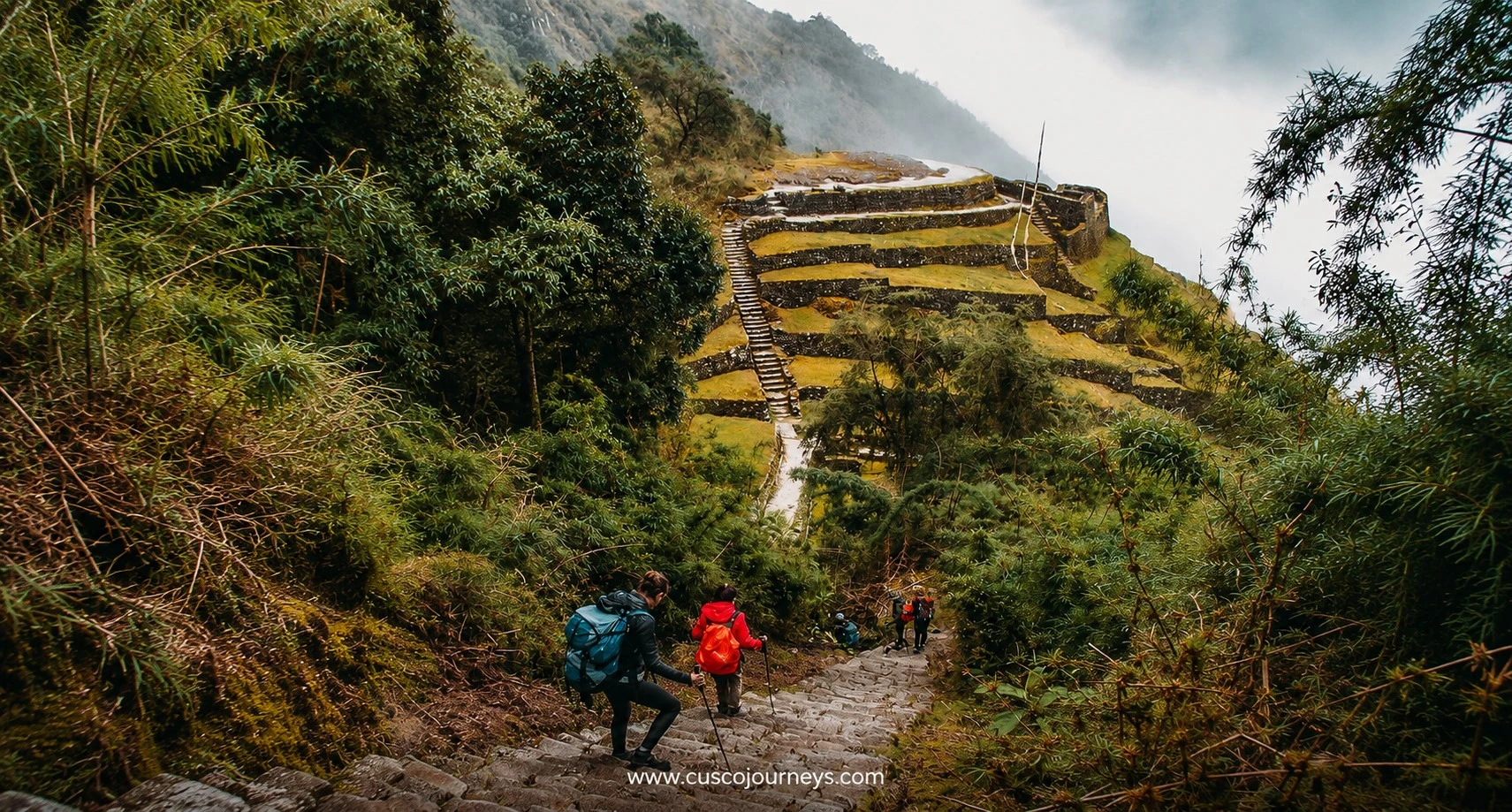 Inca Trail hiking route with trekkers descending ancient stone steps through lush Andean vegetation and terraces
